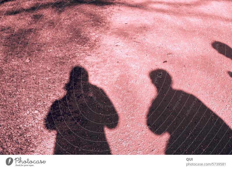 3 Schatten auf rötlichem Grund Menschen Formen silhouettenmenschen Licht und Schatten Schattenwurf Silhouette Kontrast rot Untergrund sandiger Boden