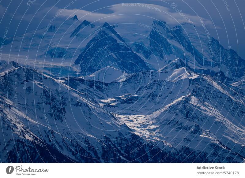 Die schroffe Schönheit der schneebedeckten Alpengipfel wird im sanften Licht der blauen Stunde eingefangen, wobei die Schatten über die ruhige Schneelandschaft spielen