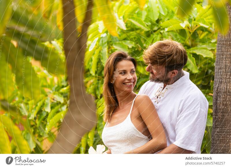 Romantisches Paar umarmt sich im tropischen Garten Liebe Umarmen Romantik Zuneigung Anschluss Zärtlichkeit Freude Lächeln Partnerschaft Fröhlichkeit Natur