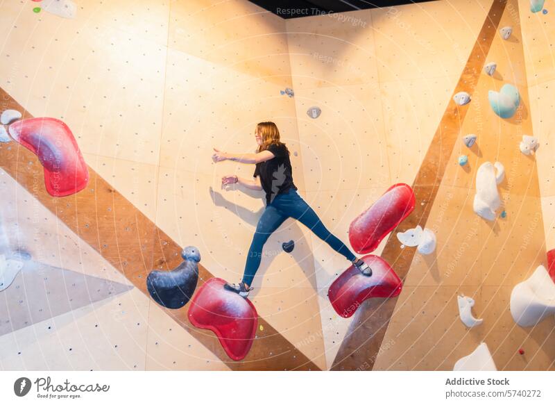 Klettern in der Halle - eine aktive Frau greift zu im Innenbereich Sport Fitness Aktivität Kletterwand erreichend dynamisch Bewegung Halt Griff Hobby
