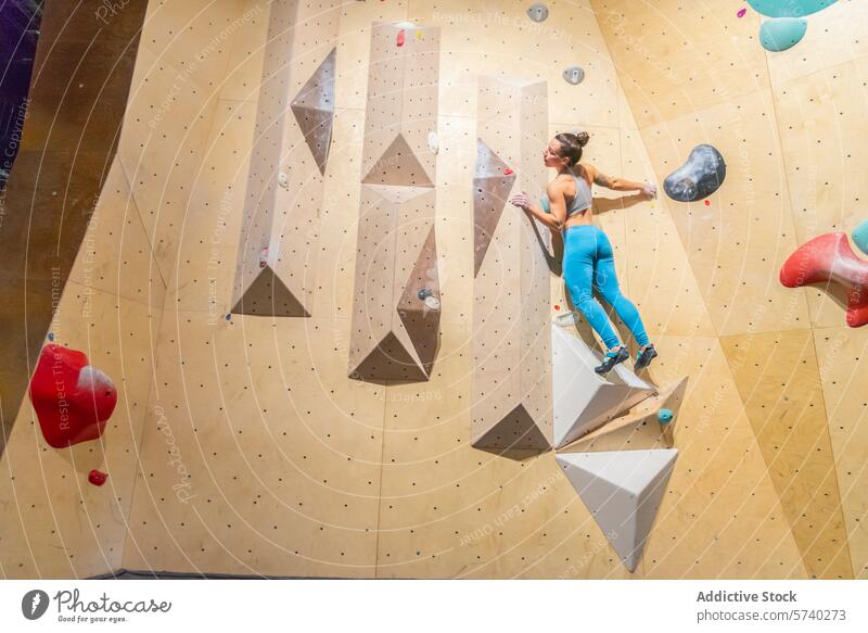 Sportliche Frau meistert anspruchsvolle Indoor-Kletterwand sportlich Klettern im Innenbereich Wand geometrisch Halt Stärke Tatkraft Übung Fitness Aufsteiger