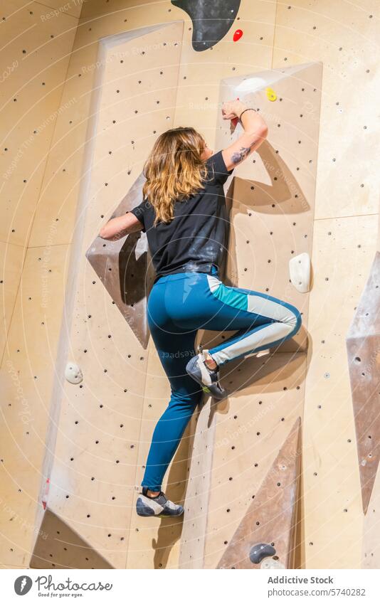 Sportliche Frau erklimmt eine Indoor-Kletterwand Klettern im Innenbereich Wand sportlich Sportbekleidung Griff Stärke Herausforderung aktiv Fitness Übung