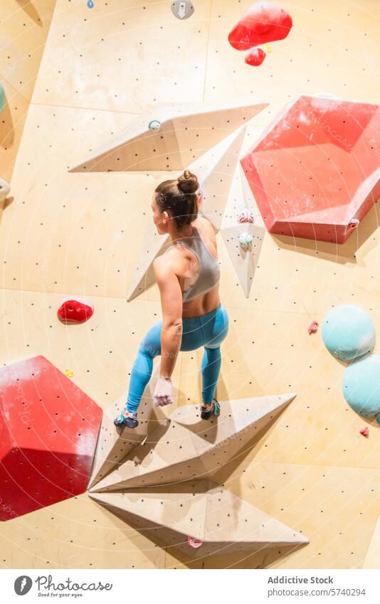 Sportlerin beim Klettern an einer Indoor-Boulderwand Aufsteiger Frau im Innenbereich Bouldern Wand Stärke Beweglichkeit Fitnessstudio Besteigung Fokus