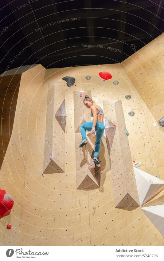 Sportliche Frau klettert an einer Indoor-Felswand Klettern im Innenbereich Felsen Wand sportlich Fitness Herausforderung Griffe Aufsteiger Aktivität Gesundheit