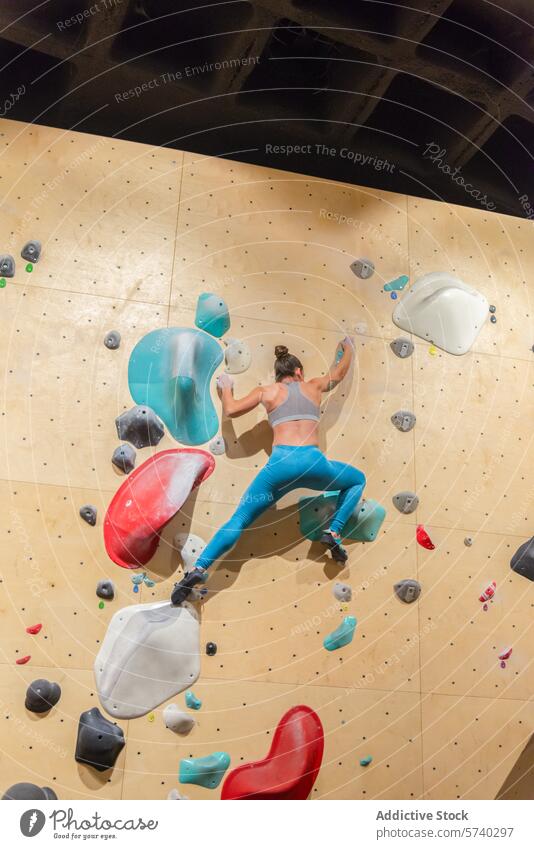 Sportliche Frau erklimmt eine Indoor-Kletterwand Klettern im Innenbereich Wand sportlich Halt Dehnung Erreichen farbenfroh Aufstieg Übung Sportkleidung Fitness