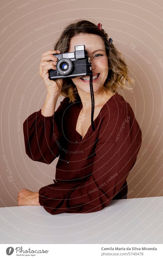 Junge Frau schaut durch eine alte Kamera. Foto im Studio mit isoliertem Hintergrund. Erwachsener schön Schönheit blond Fotokamera Kaukasier Konzept Kreativität