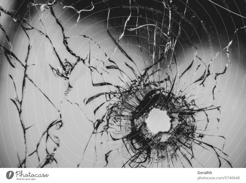 Einschussloch in gesprungenem Fensterglas abstrakt Unfall Hintergrund gebrochen zerbrochenes Glas kaputtes Fenster Gewehrkugel Einschusstreffer Einschussstelle