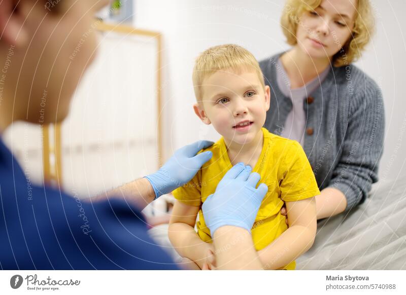 Ein niedlicher kleiner Junge und seine Mutter haben einen Termin bei einem Kinderarzt. Der HNO-Arzt untersucht die Lymphknoten eines kleinen Patienten.