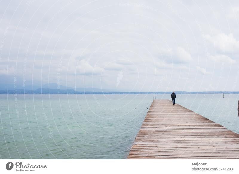 Unbekannter Mann steht auf dem Pier über dem Gardasee Horizont Perspektive Ruhe Portwein Landschaft idyllisch Fundstück Meereslandschaft Ferien Stille Ehrfurcht