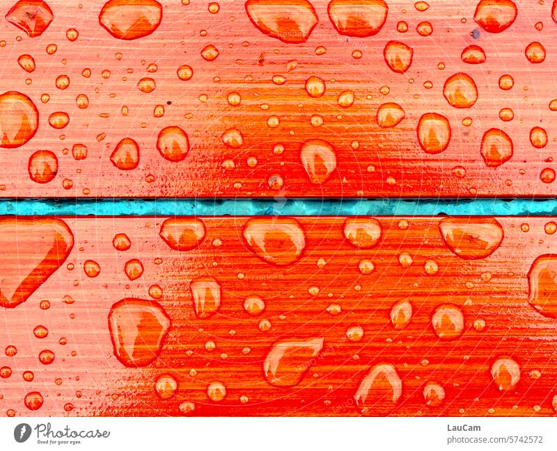 wasserabweisend - Regentropfen auf orangenem Holz Wassertropfen abperlen abperlend nass Tropfen feucht Schietwetter farbig strahlend Regentag Nahaufnahme