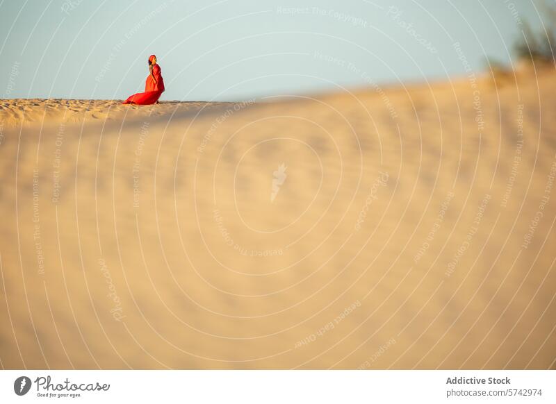 Elegante Frau in rotem Kleid auf einer Wüstendüne sitzend rotes Kleid wüst Dunes Sand Sitzen elegant Einsamkeit Natur im Freien Mode Landschaft Gelassenheit