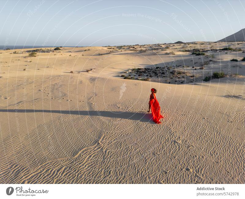 Elegante Frau in rotem Kleid spaziert durch Wüstendünen rotes Kleid wüst Dunes Sand wandern elegant Kontrast Gelassenheit Landschaft fließend schlendern riesig