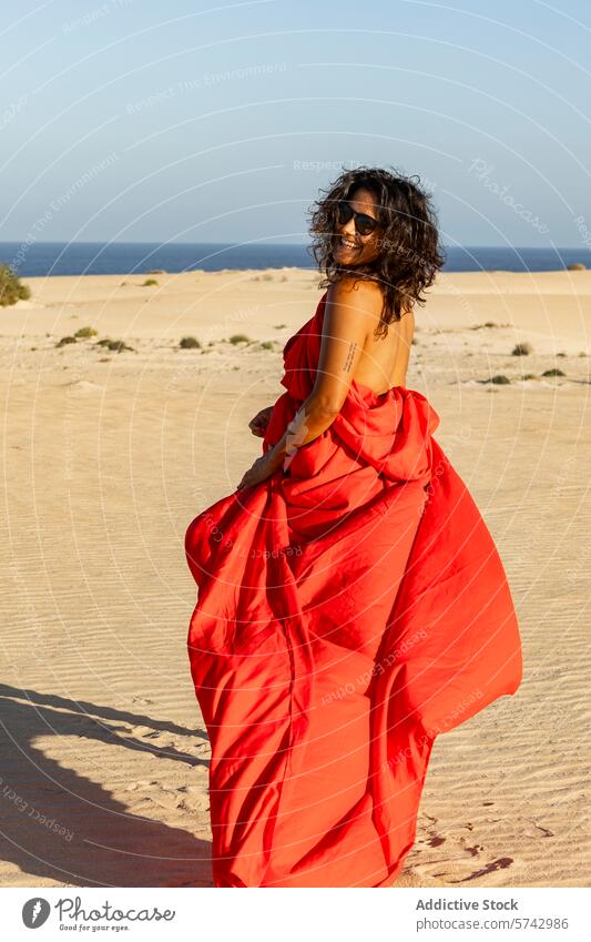 Fröhliche Frau in Rot schaut auf Wüstendünen weg rotes Kleid wüst Dunes sandig MEER in die Kamera schauen heiter freudig fließendes Kleid Mode Natur im Freien