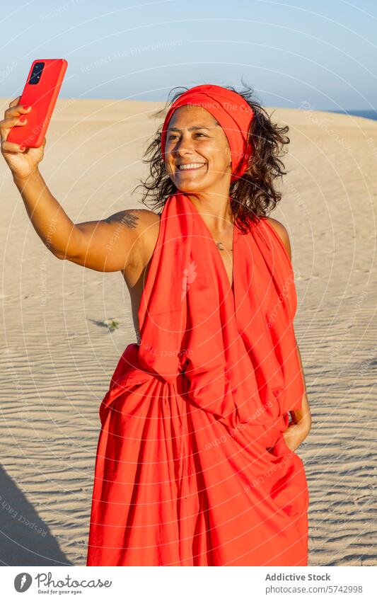 Frau im roten Kleid nimmt Selfie in der Wüste wüst Düne Handy Kopftuch Lächeln freudige sandig Bildschirm Blick auf den Bildschirm Gerät Apparatur Glück Mode