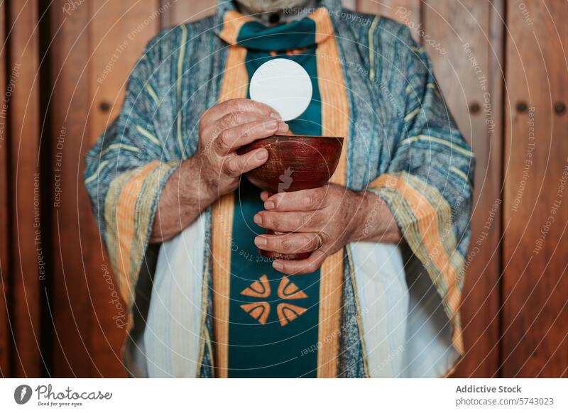 Ein anonymer Priester erhebt die eucharistische Hostie über einen Kelch, ein zentrales Ritual bei der Feier des christlichen Abendmahlsgottesdienstes Wirt
