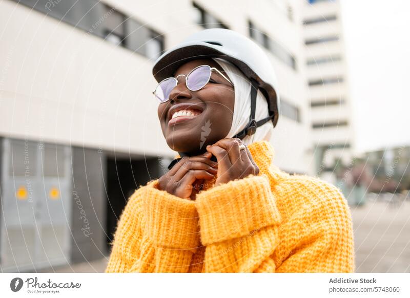 Fröhliche städtische Frau mit Fahrradhelm schwarz urban Großstadt Glück Lächeln im Freien Fröhlichkeit Freude pulsierend gelber Pullover Mode Straßenkleidung