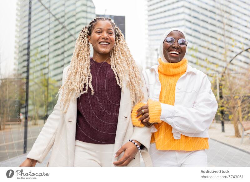 Zwei fröhliche schwarze Frauen genießen die gemeinsame Zeit in einer städtischen Umgebung Großstadt urban Freundschaft heiter Brille Hochhaus schlendern Paar