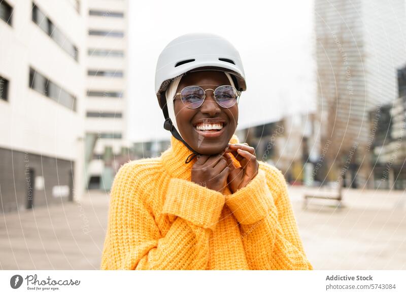 Fröhliche Frau mit Helm in städtischer Umgebung schwarz Afroamerikaner Schutzhelm Sicherheit Brille Lächeln urban Großstadt heiter Freude Fangvorrichtung Mode