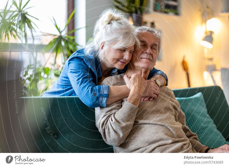 Porträt eines glücklichen älteren Paares, das zu Hause auf dem Sofa sitzt Menschen Kaukasier graue Haare lässig Tag im Innenbereich echte Menschen