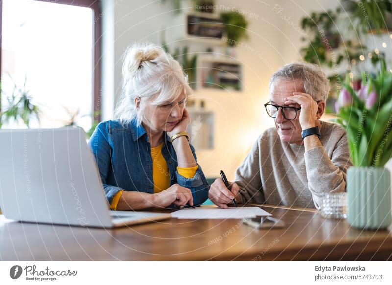Ein älteres Ehepaar sitzt am Tisch und diskutiert über die Finanzen seines Hauses Menschen Kaukasier graue Haare lässig Tag Porträt im Innenbereich