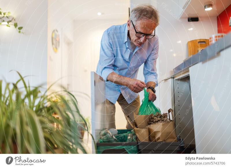 Älterer Mann sortiert zu Hause den Müll in die Recyclingtonne Menschen Kaukasier graue Haare lässig Tag Porträt im Innenbereich echte Menschen weiße Menschen