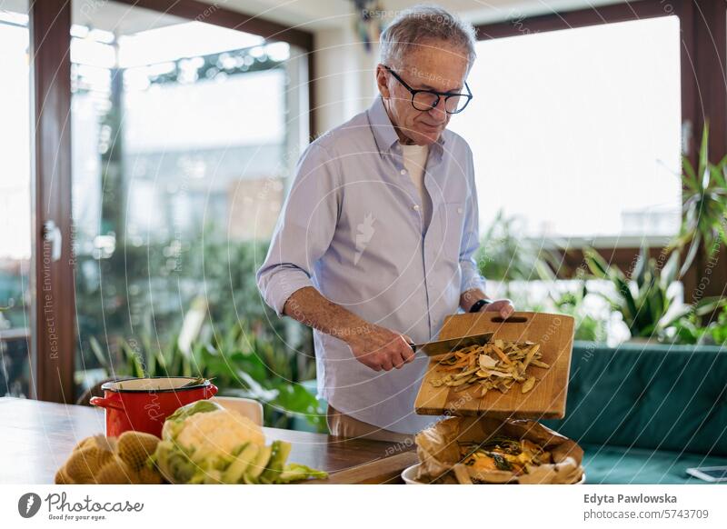 Älterer Mann bei der Herstellung von Kompost aus Speiseresten zu Hause Menschen Kaukasier graue Haare lässig Tag Porträt im Innenbereich echte Menschen