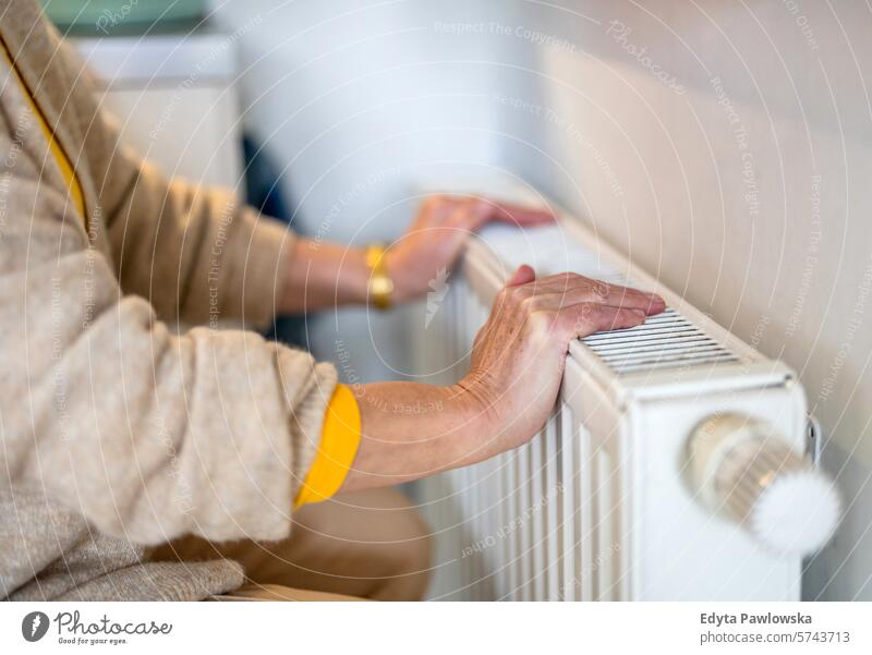 Ältere Frau prüft Heizkörper in ihrer Wohnung Heizung Wärme warm Temperatur Komfort Küche Hausheizung Thermostat Klima Kontrolle Elektrizität Hände