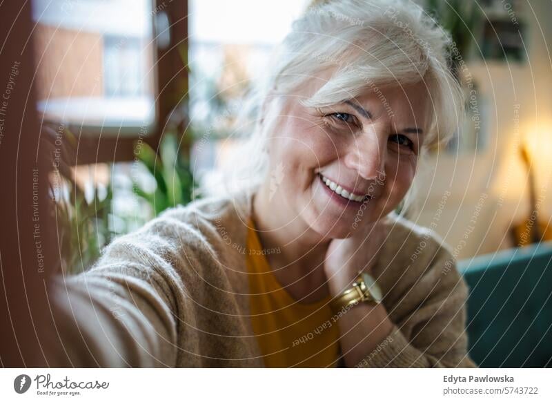 Porträt einer lächelnden älteren Frau, die ein Selfie zu Hause macht Menschen lässig Tag im Innenbereich echte Menschen weiße Menschen Erwachsener reif