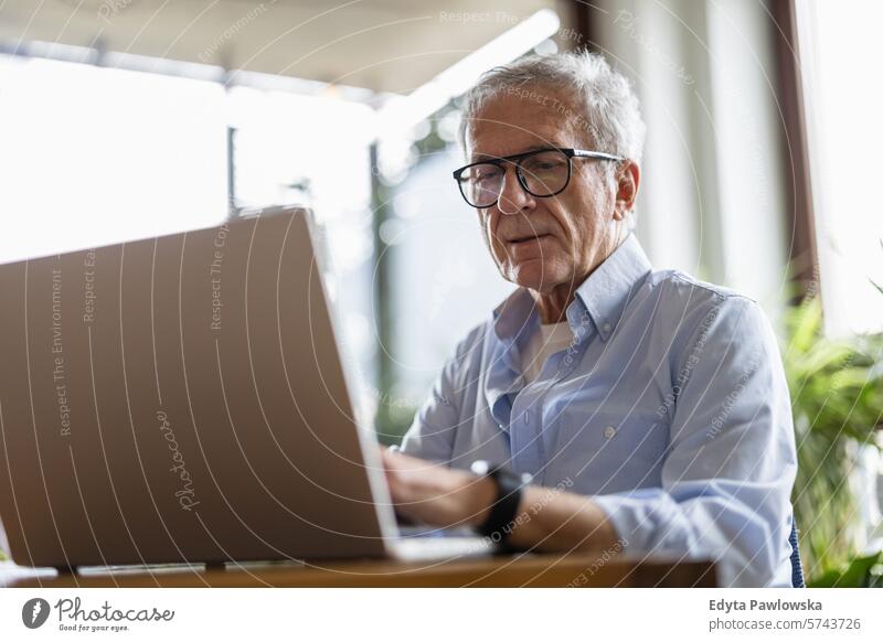 Älterer Mann benutzt Laptop zu Hause Menschen Kaukasier graue Haare lässig Tag Porträt im Innenbereich echte Menschen weiße Menschen Erwachsener reif