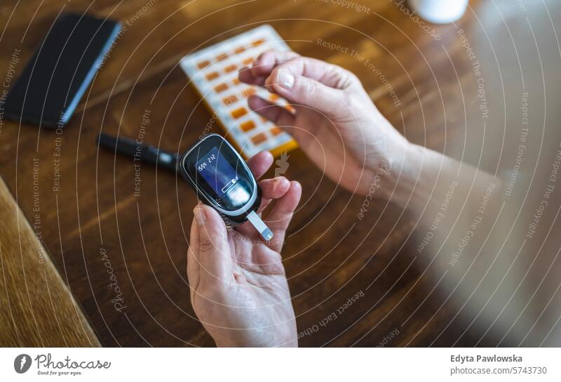Ältere Frau prüft ihren Blutzuckerspiegel, während sie zu Hause sitzt Überprüfung Glaukometer Hände Tisch Gesundheit geduldig Krankheit Sitzen Blutzuckertest