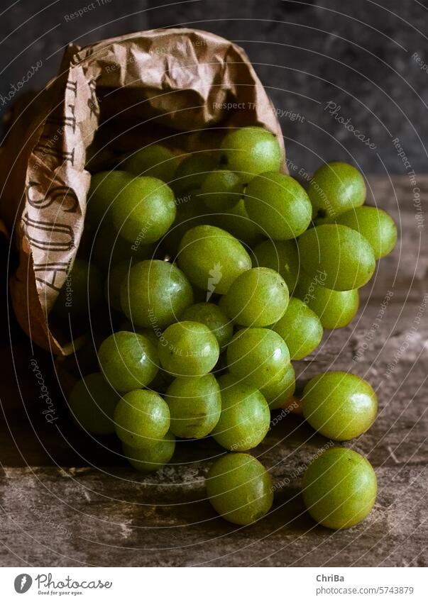 Grüne Weintrauben fallen aus einer braunen Obsttüte auf einen rustikalen Tisch weintrauben grün sauer natürlich papiertüte markt tisch lecker obst gesund