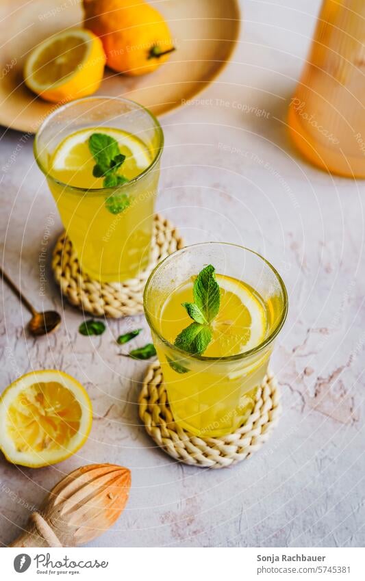 Erfrischungsgetränk mit Zitrone in zwei Gläser Getränk Saft kalt Sommer Glas Limonade trinken Zitrusfrüchte Scheibe Minze Blatt Frucht Cocktail süß tropisch