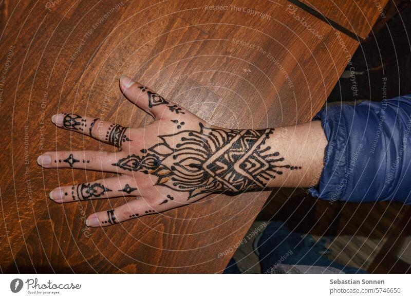 Weibliche Hand mit schwarzer Henna-Tätowierung mit hölzernem Hintergrund menschlich Tattoo Liebe vereinzelt Arme Finger Pflege Haut Tatoo Frau Menschen offen