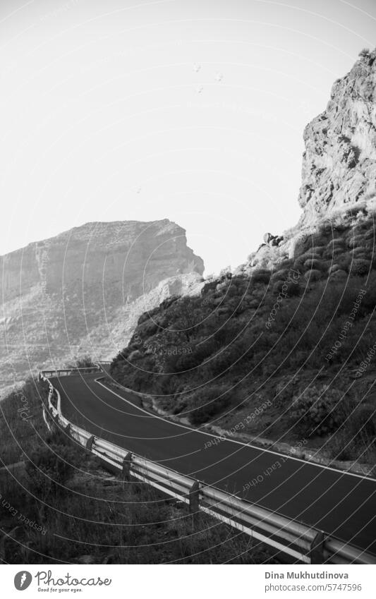 Schwarz-Weiß-Foto einer kurvenreichen Straße in den Bergen mit Blick auf die Gipfel der Felsen und Berge bei bewölktem Wetter auf der Insel Gran Canaria