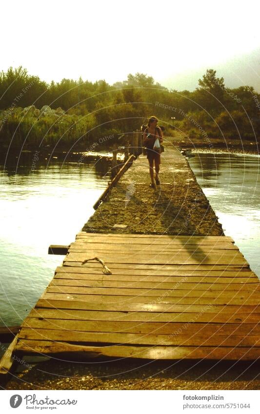 Frau wandert auf einem Holzsteg wandern Fluss exotisch Steg holzsteg Abendstimmung Sommer Reise Urlaub Landschaft Natur pilgern Pilgerin Junges Fräulein Ferien