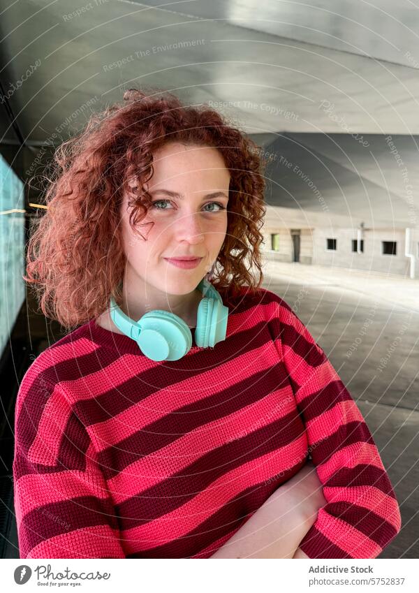 Junge rothaarige Frau mit Kopfhörern in städtischer Umgebung jung krause Haare gestreiftes Hemd urban Selbstvertrauen Porträt lässig Mode Stil Musik Freizeit