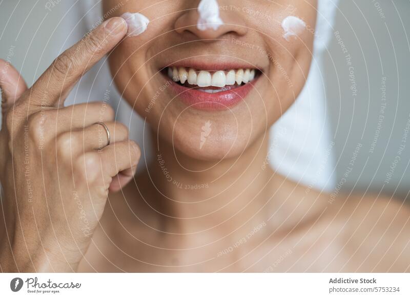 Frau beim Eincremen des Gesichts mit einem fröhlichen Lächeln Gesichtscreme Hautpflege Schönheit Feuchtigkeitscreme Anwendung Nahaufnahme Fröhlichkeit Freude