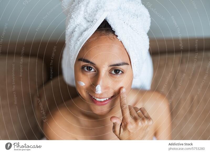 Junge Frau trägt lächelnd Gesichtscreme auf Hautpflege Gesichtsbehandlung Sahne Feuchtigkeitscreme Schönheit Lächeln jung strahlend Handtuch Kopf bewerben