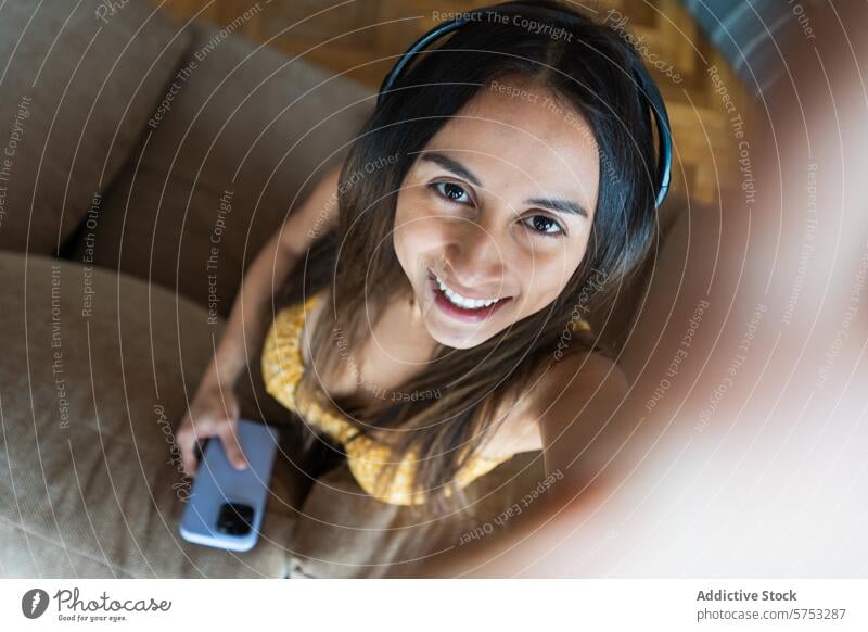 Junge Frau genießt Musik zu Hause mit Kopfhörern heimwärts Smartphone Selfie Liege gemütlich Sitzen Lächeln Freizeit Erholung Technik & Technologie lässig