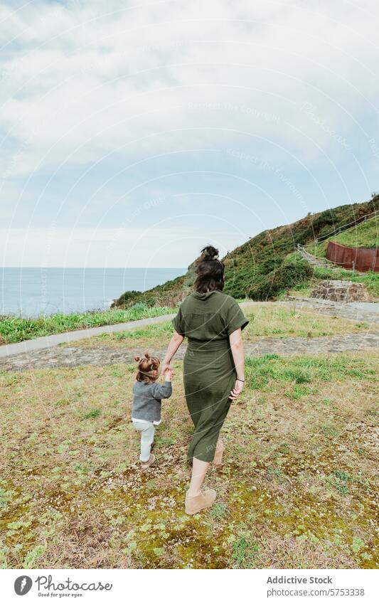 Mutter und Kind beim Spaziergang auf dem Küstenpfad Hand in Hand Küstenstreifen Weg wolkig Himmel malerisch im Freien Familie binden Kindererziehung Kleinkind