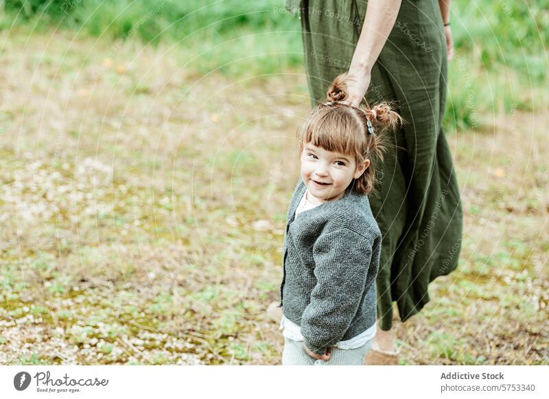 Fröhliches Kind, das mit einem Erwachsenen in der Natur Händchen hält Erwachsener Lächeln Glück Händchenhalten grasbewachsen Feld Pflege Anschluss Mädchen