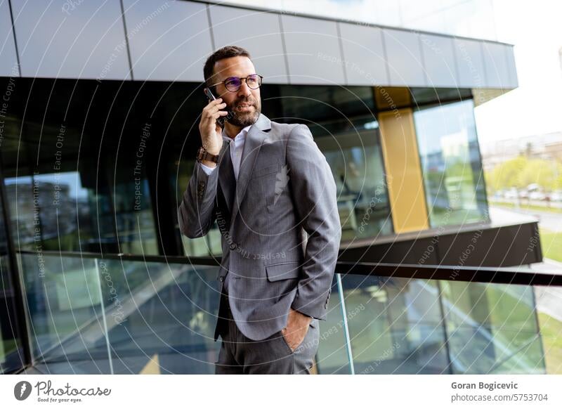 Selbstbewusster Geschäftsmann im scharfen Anzug vor einer modernen Glasfassade eines Büros. Generative KI Ehrgeiz Architektur Gebäude Business Karriere
