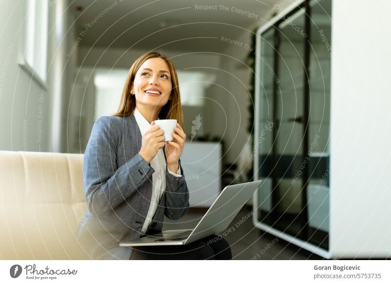 Elegante Geschäftsfrau, die an einem sonnigen Büromorgen eine ruhige Kaffeepause genießt Laptop Morgen Sonnenlicht professionell Arbeit Pause elegant bereit