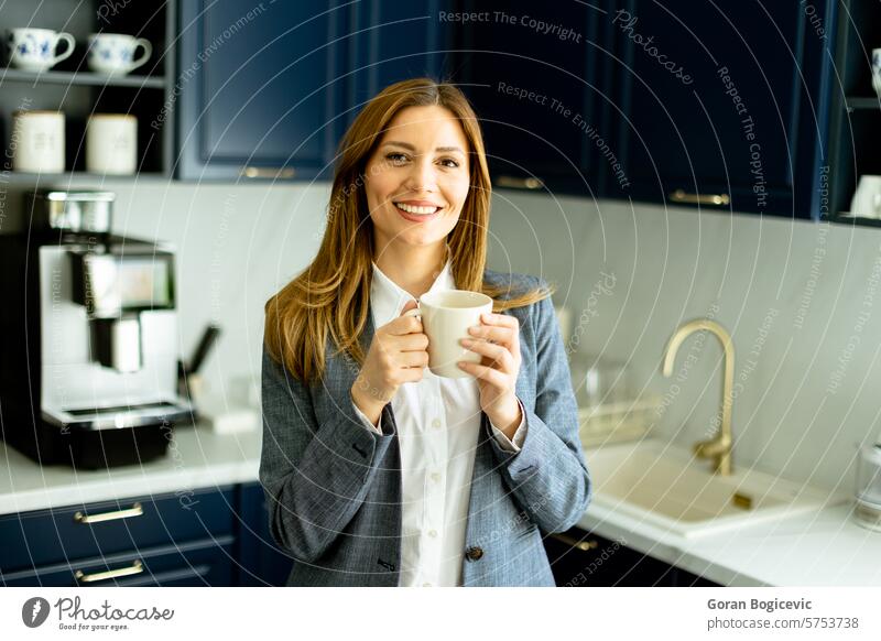 Selbstbewusste Geschäftsfrau bei einer Kaffeepause in einer modernen Büroküche Pause Lächeln Beteiligung Becher entspannend stylisch blau professionell Kleidung