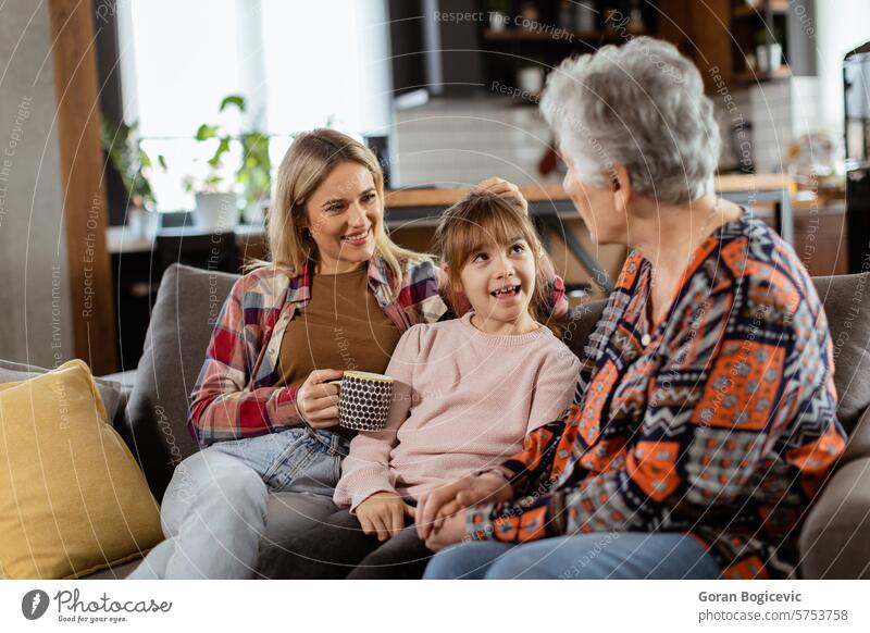 Zusammenführung der Generationen: Großmutter, Tochter und Enkelin tauschen an einem gemütlichen Nachmittag Geschichten aus Bonden Freizeitkleidung plaudernd