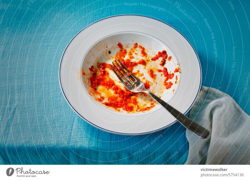 Verschmutztes Geschirr mit Gabel ausleeren dreckig Speise Lebensmittel Saucen rot Küche Hausarbeit Tomatensauce unsauber blau Teller heimwärts Abendessen