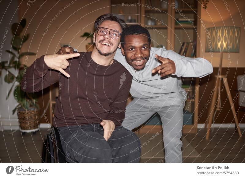 Porträt eines jungen Mannes mit Behinderung in Vorderansicht, der mit einem afroamerikanischen Freund auf einer Hausparty posiert, aufgenommen mit Blitzlicht