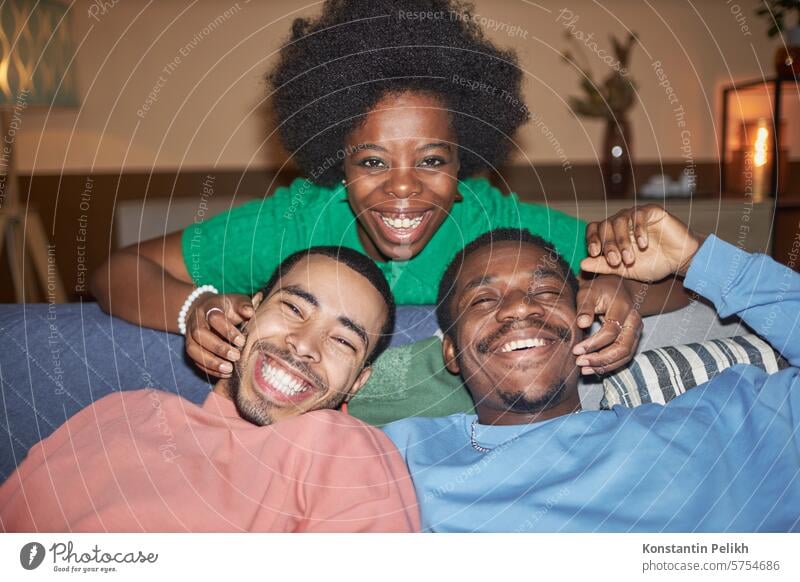 Frontalaufnahme einer Gruppe von drei Freunden mit einer jungen schwarzen Frau, die während einer Party mit Blitzlicht in die Kamera lächelt heimwärts