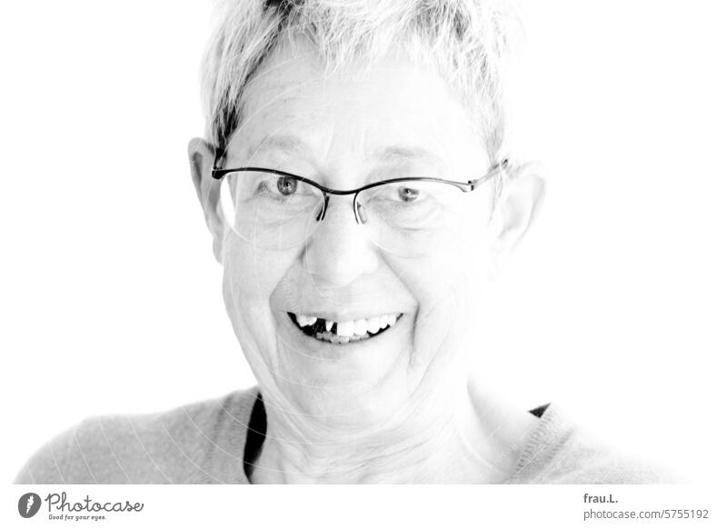 In ein Krokantei gebissen – frohe Ostern! Frau Portrait Gesicht alt Porträt graue Haare Schlupflider Falten Brille Zahnlücke Provisorium Zahnbehandlung