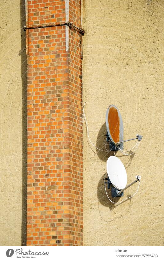 zwei Satellitenschüsseln an einer Hauswand neben einem Ziegelschornstein Schornstein SAT-Anlage Sat-Schüssel Satellitenanlage Fernsehen Satellitenantenne